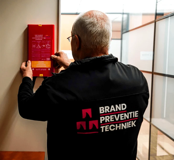 Keurmeester van Brandpreventie Techniek controleert een blusdeken aan de wand